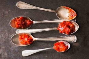 Five spoons each topped with a dollop of sambal oelek.
