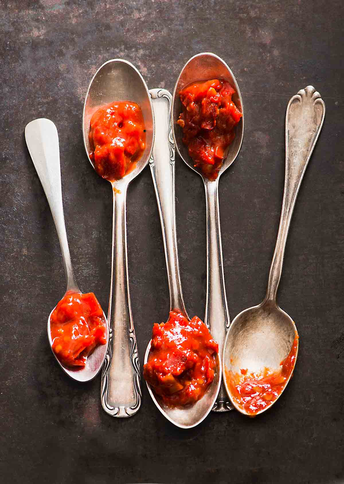 Five spoons each topped with a dollop of sambal oelek.