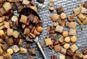 Spicy Chex mix scattered on a baking sheet with a spoon lying in the middle.