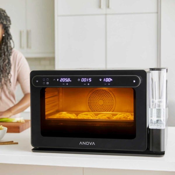 Anova Precision Oven on with woman chopping scallions on left.