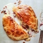 A halved round of baked Bried stuffed with cranberries in a puff pastry shell.