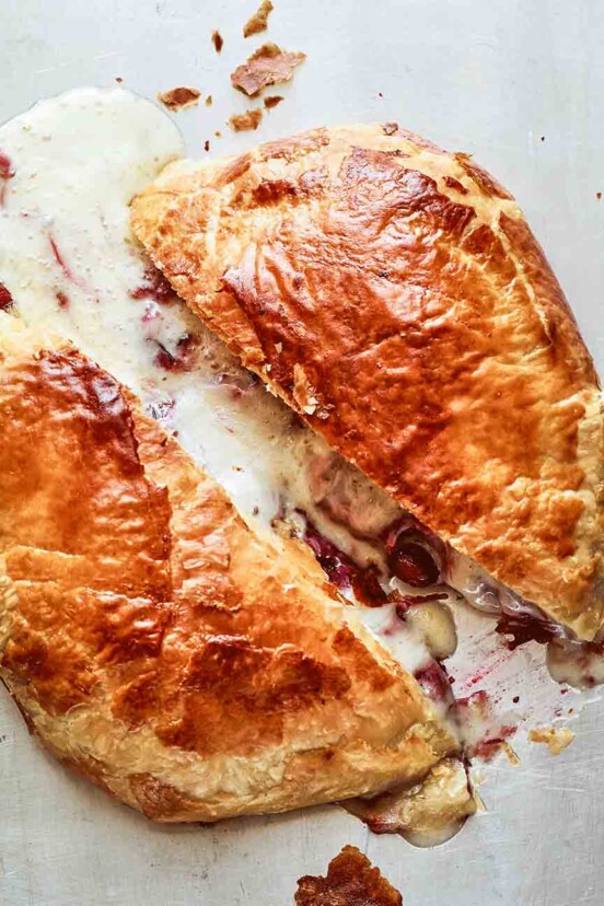 A halved round of baked Bried stuffed with cranberries in a puff pastry shell.
