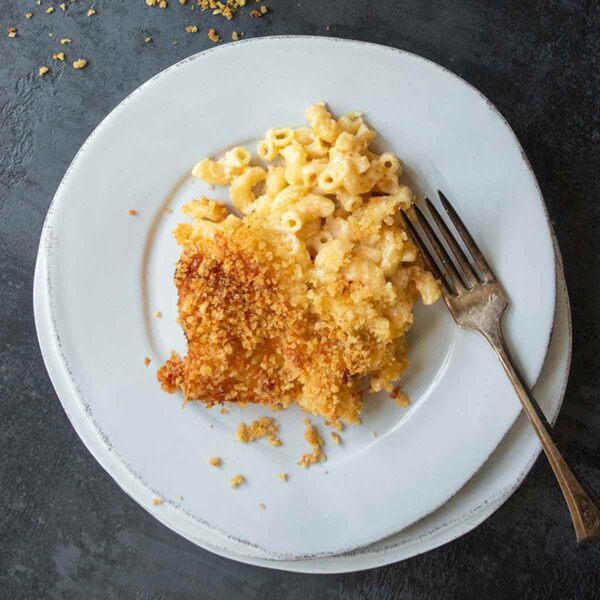 A plate of macaroni and cheese with a fork on the side.