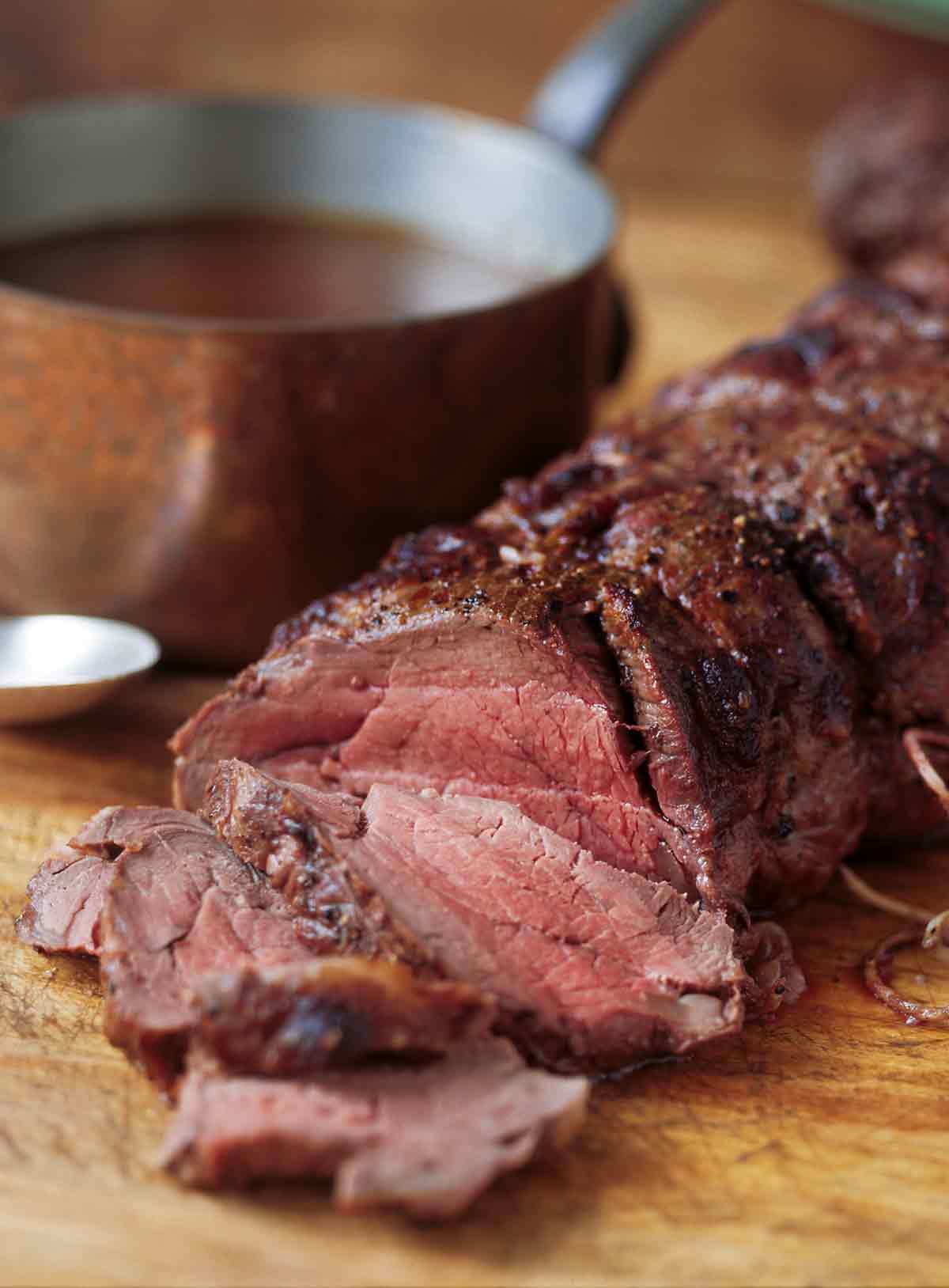 A perfectly roasted beef tenderloin with Madeira sauce on the side ion a copper pot