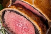 Close-up of a beef Wellington on a plate with a sprig of rosemary