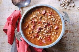 Bowl of black-eyed peas in a tomato broth on a sheet of wood