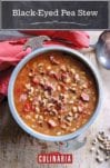 Bowl of black-eyed peas in a tomato broth on a sheet of wood