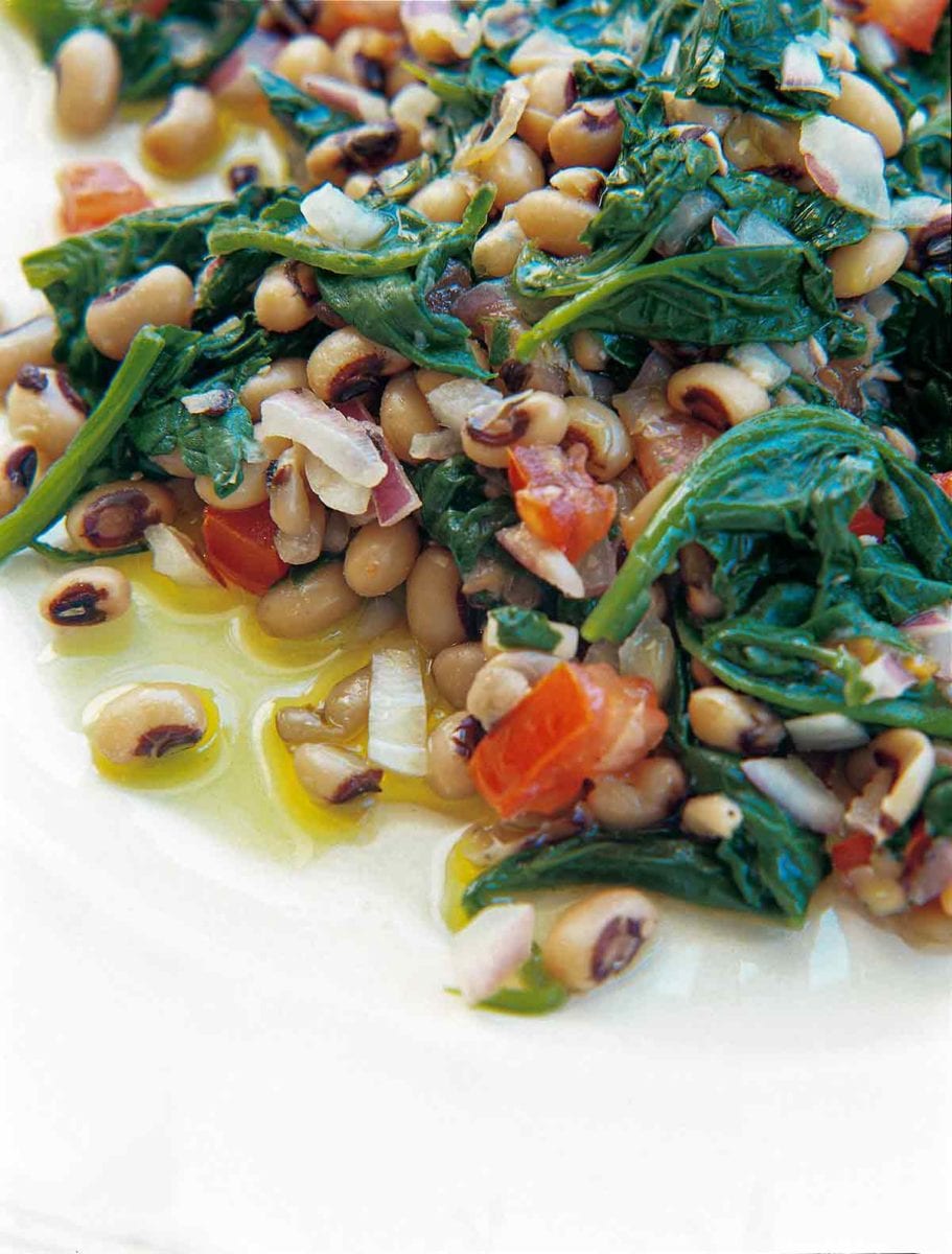 Black-eyed peas, spinach, red onion, and red pepper on a white plate.