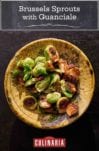 A wooden bowl filled with roasted Brussels sprouts with guanciale.