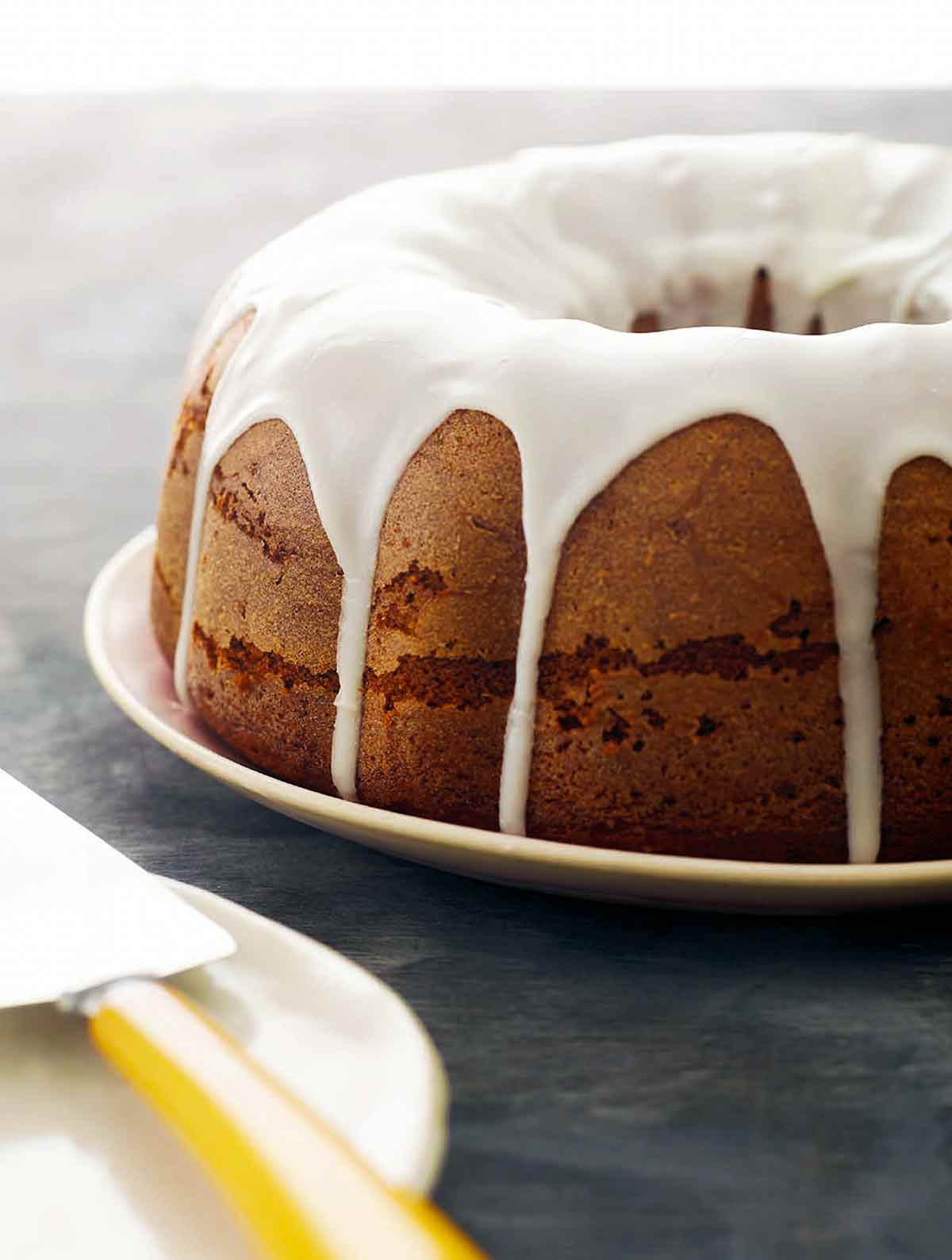 En glaserad pumpa-pundtårta på en tallrik--en pumpa Bundt-tårta med en mjölk-socker hälld glasyr.