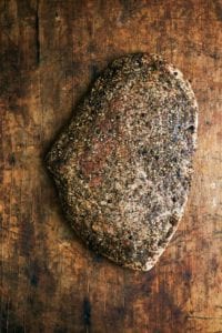 A slab of homemade Guanciale on a wooden board.