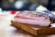A slab of homemade Guanciale on a wooden board.