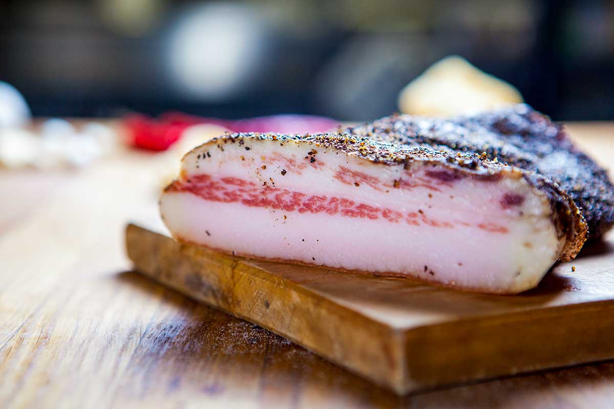 A slab of homemade Guanciale on a wooden board.