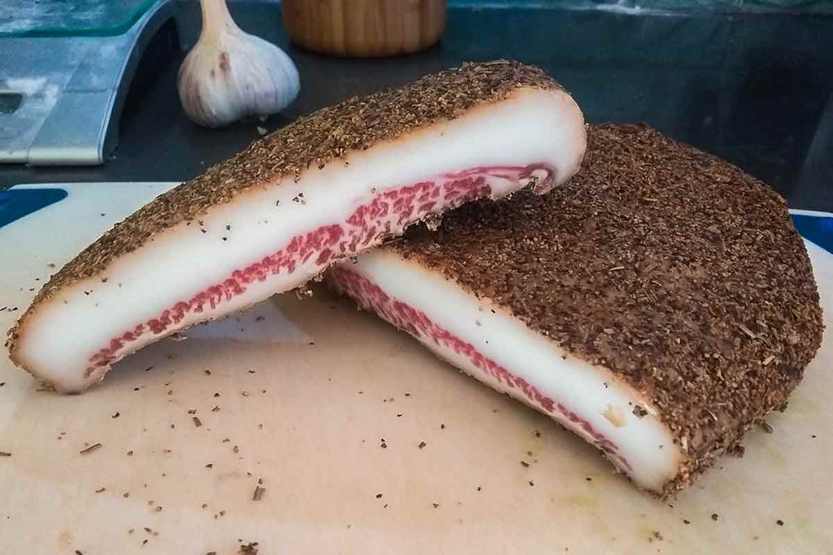 A slab of homemade Guanciale on a wooden board.