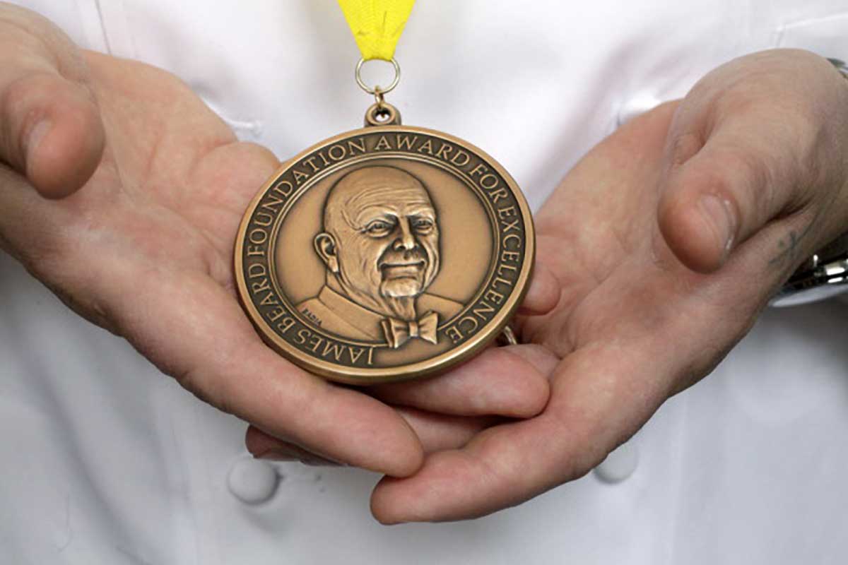 A chef displaying a James Beard award, featured in the podcast Talking With My Mouth Full Ep. 34: An Intimate Look at James Beard with John Birdsall.