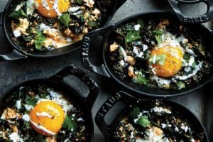 Mini Staub skillets filed with kale shakshuka--eggs, kale, and spices