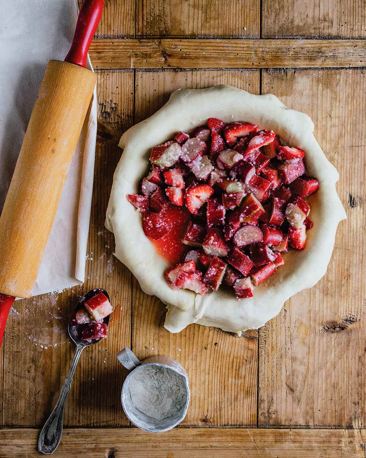 An unbaked pie crust filled with strawberries and rhubarb for the podcast Talking With My Mouth Full, Ep. 33: Kate McDermott: How to Make Pie Crust.