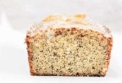 A cut loaf of lemon-poppy seed cake on a white background