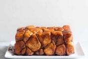 A loaf of monkey bread--balls of caramel-coated bread dough dripping caramel sauce on a rectangle plate