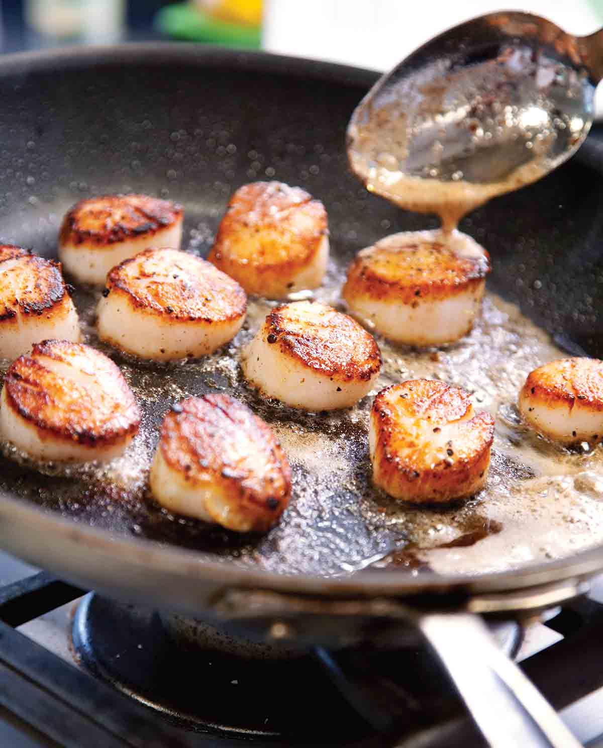 A skillet filled with pan seared scallops cooked in butter