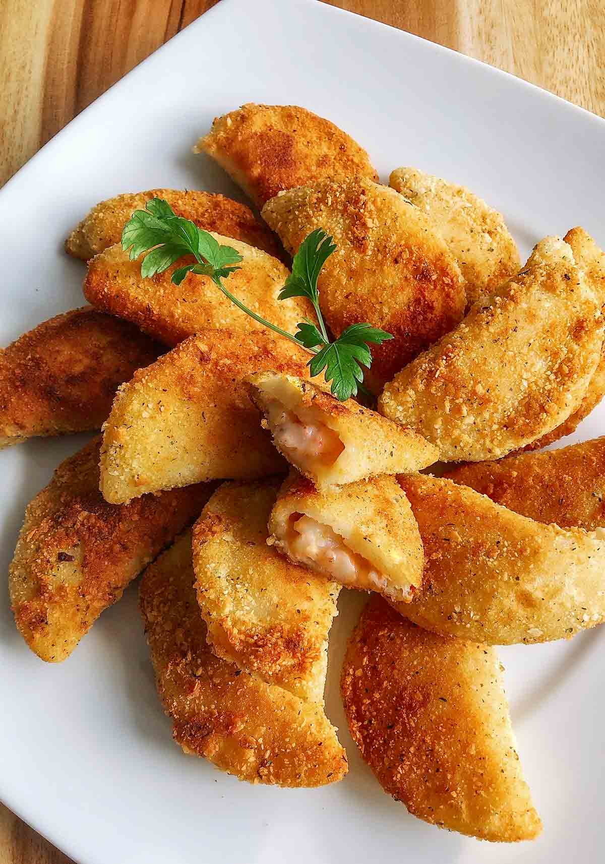 A platter of rissois de Camarao--or Portuguese shrimp turnovers--with one turnover cut open resting on top.