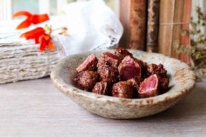 A ceramic bowl filled with chunks of shaking beef.