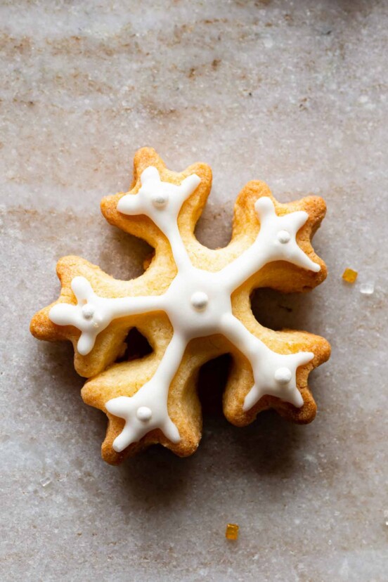 A snowflake cookies frosted with royal icing on a granite background