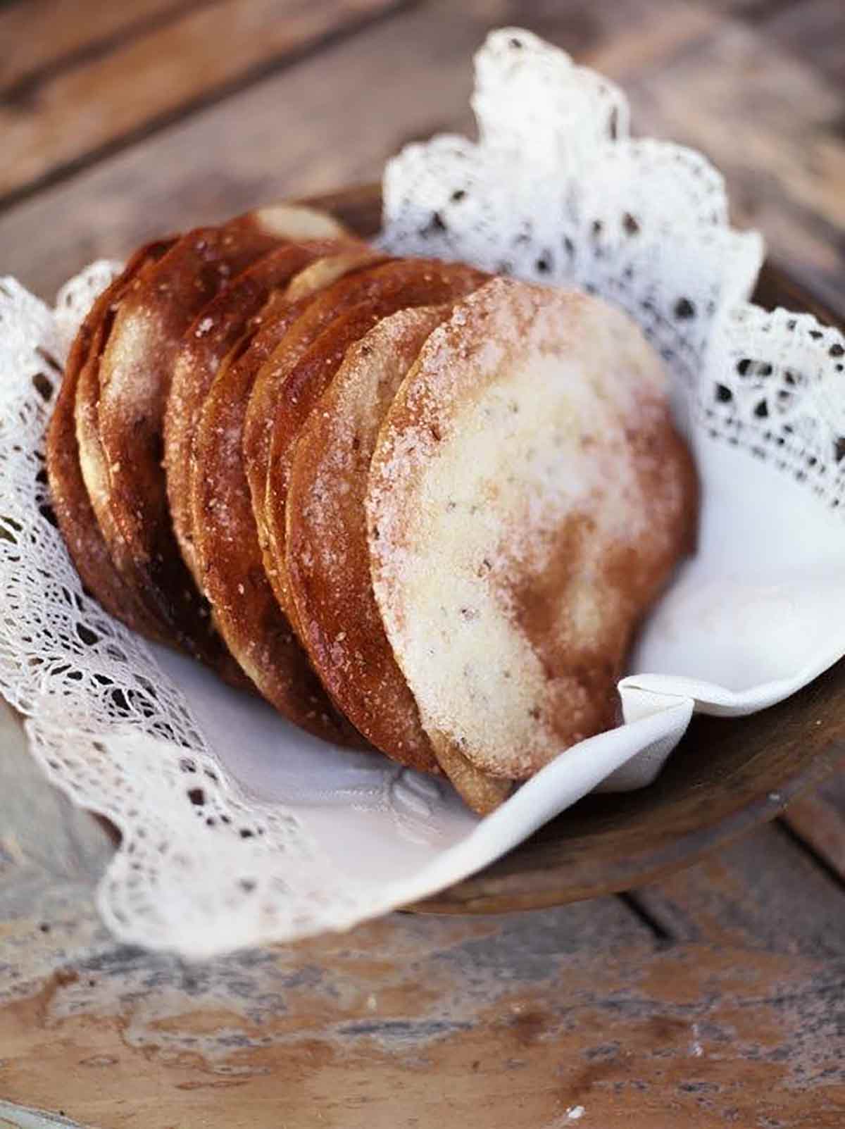 Several Spanish olive oil tortas in a bowl lined with a lace linen cloth.