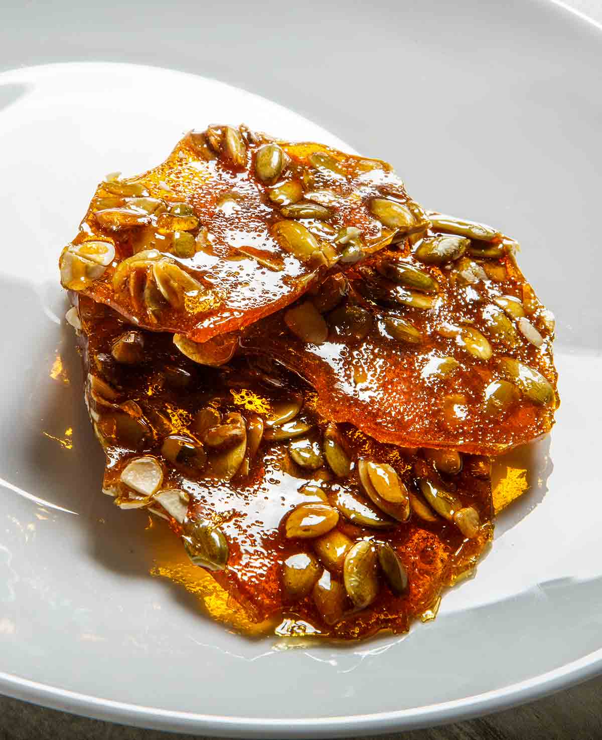 Three pieces of spicy pepita brittle on a white plate.