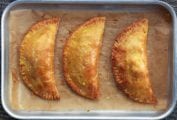 Three leftovers turnovers on a parchment-lined small rimmed baking sheet.