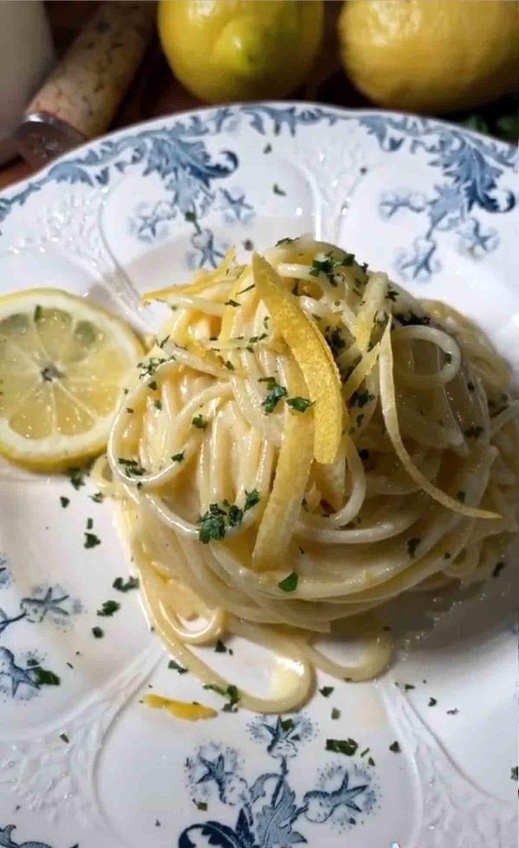 A plate of Sophia Loren's lemon pasta with two pieces of lemon zest and chopped parsley on top