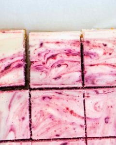 A slab of red wine cherry cheesecake bars cut into squares.
