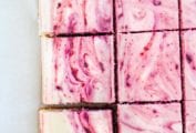 A slab of red wine cherry cheesecake bars cut into squares.