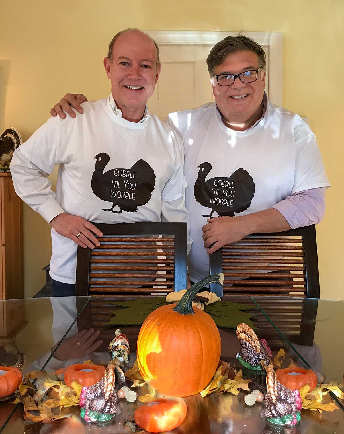 A photograph of David and the One in Thanksgiving t-shirts for the writing "We're Having a Small Thanksgiving and I'm Okay With That"
