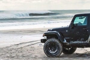 A black Jeep parked on the beach as an option for an untraditional Thanksgiving.