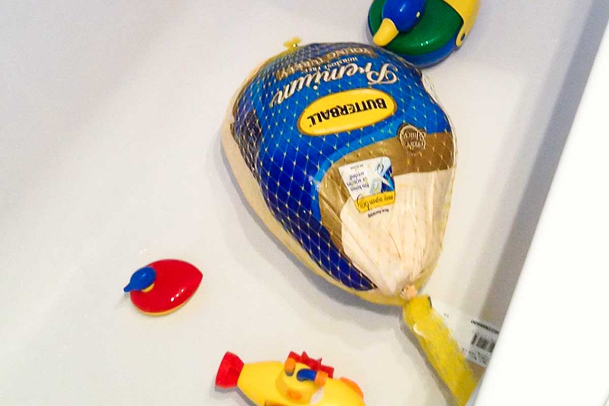 A Butterball turkey in a bathtub with children's toys for suggestions on how to thaw a turkey on an untraditional Thanksgiving day.