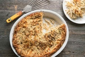 Oval dish with cacio e pepe kugel, a cheese and pepper casserole with fettuccine and ricotta and Pecorino cheeses baked golden