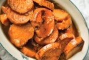 Sliced candied sweet potatoes in an oval baking dish.