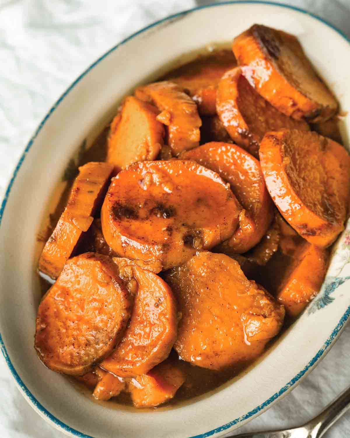 Sliced candied sweet potatoes in an oval baking dish.