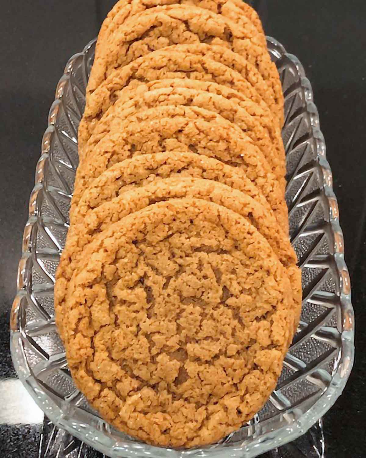 A stack of chewy molasses cookies arranged in a glass dish.