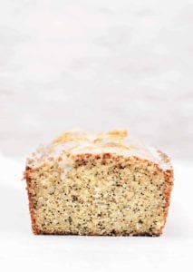 A cut citrus poppy seed cake with a white glaze.