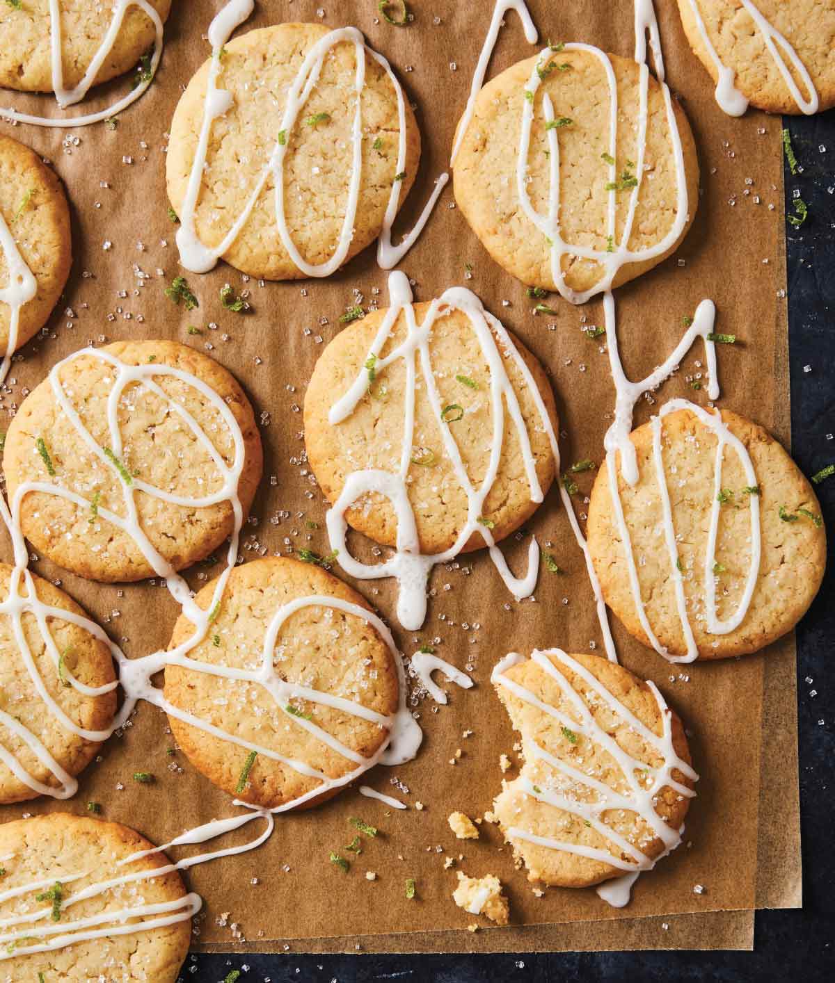 Coconut lime cookies drizzled with icing and garnished with lime zest on wax paper.