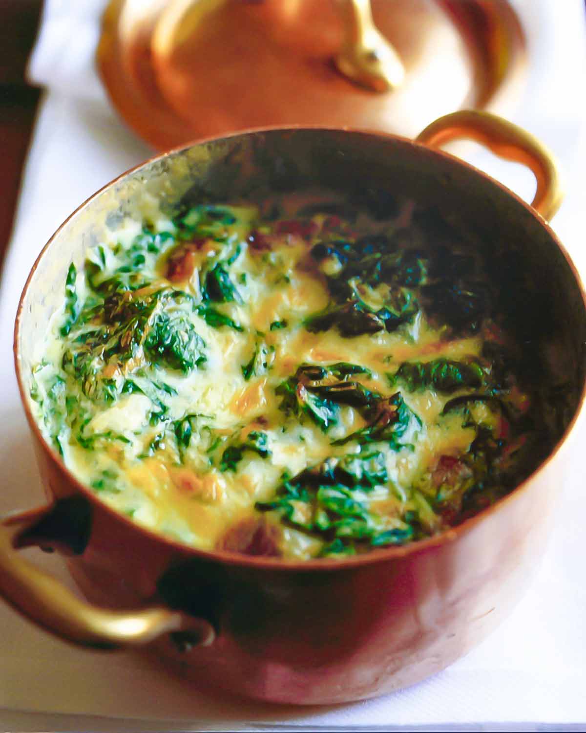 A copper pot filled with creamed spinach.