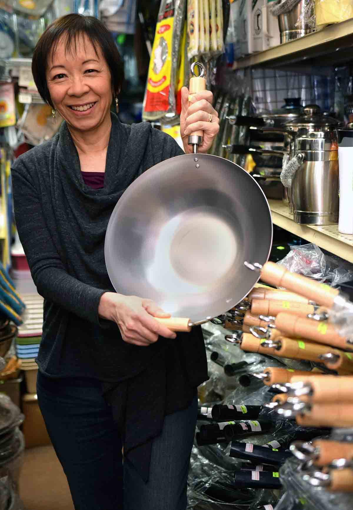 Photo of Grace Young in a store holding a wok.