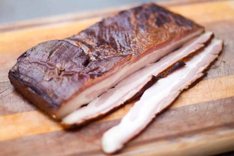 Homemade maple-espresso bacon on a cutting board on a stone slab