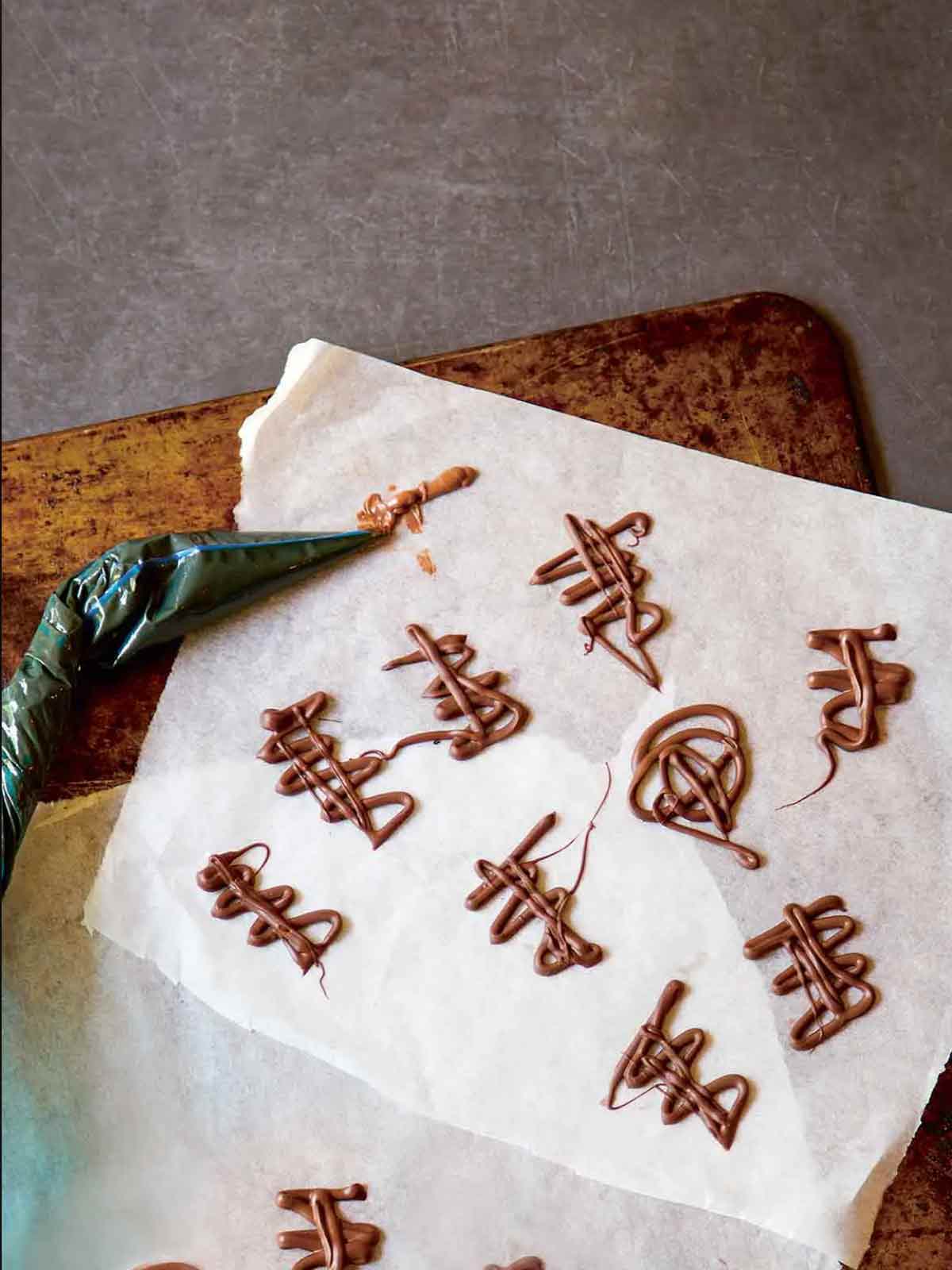 Squiggles of melted chocolate on a piece of parchment with a piping bag lying beside.