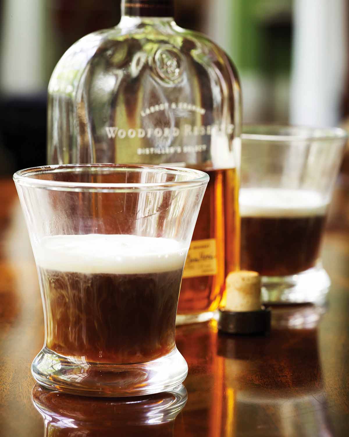 Two glasses half-filled with Kentucky coffee and an open bottle of bourbon between them.