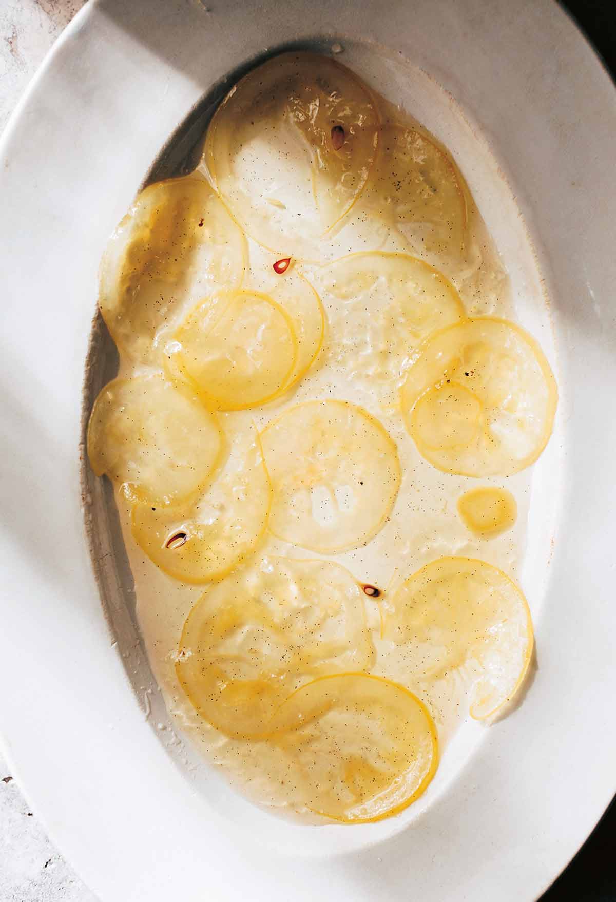 Slices of lemon confit on a white oval platter.