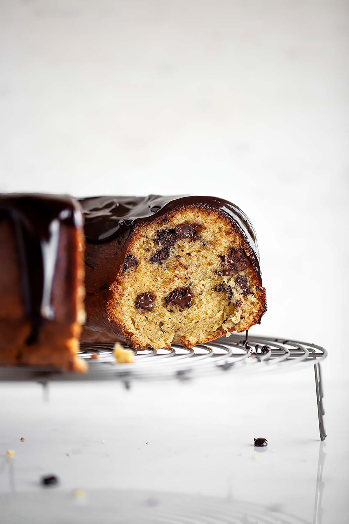 A partially cut orange chocolate chunk cake on a round wire rack.