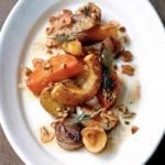 A white plate topped with roasted root vegetables and Marcona almonds.